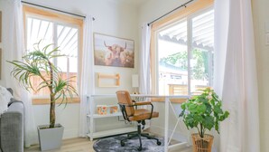 Une pièce comprenant un bureau, une chaise, des plantes en pot et une fenêtre avec des rideaux.
