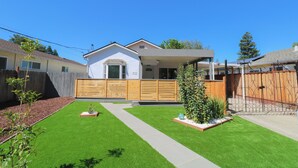 Une maison moderne dotée d’un patio couvert, d’une pelouse bien entretenue et d’une clôture en bois.