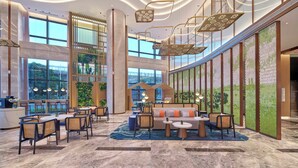 A spacious lobby with a high ceiling, modern lighting, and a seating area with tables and chairs. - Hilton Garden Inn Xiamen Tong'an (Xiamen)