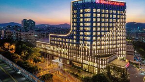 A modern hotel with a distinctive curved facade, multiple floors, and a prominent sign. - Hilton Garden Inn Xiamen Tong'an (Xiamen)