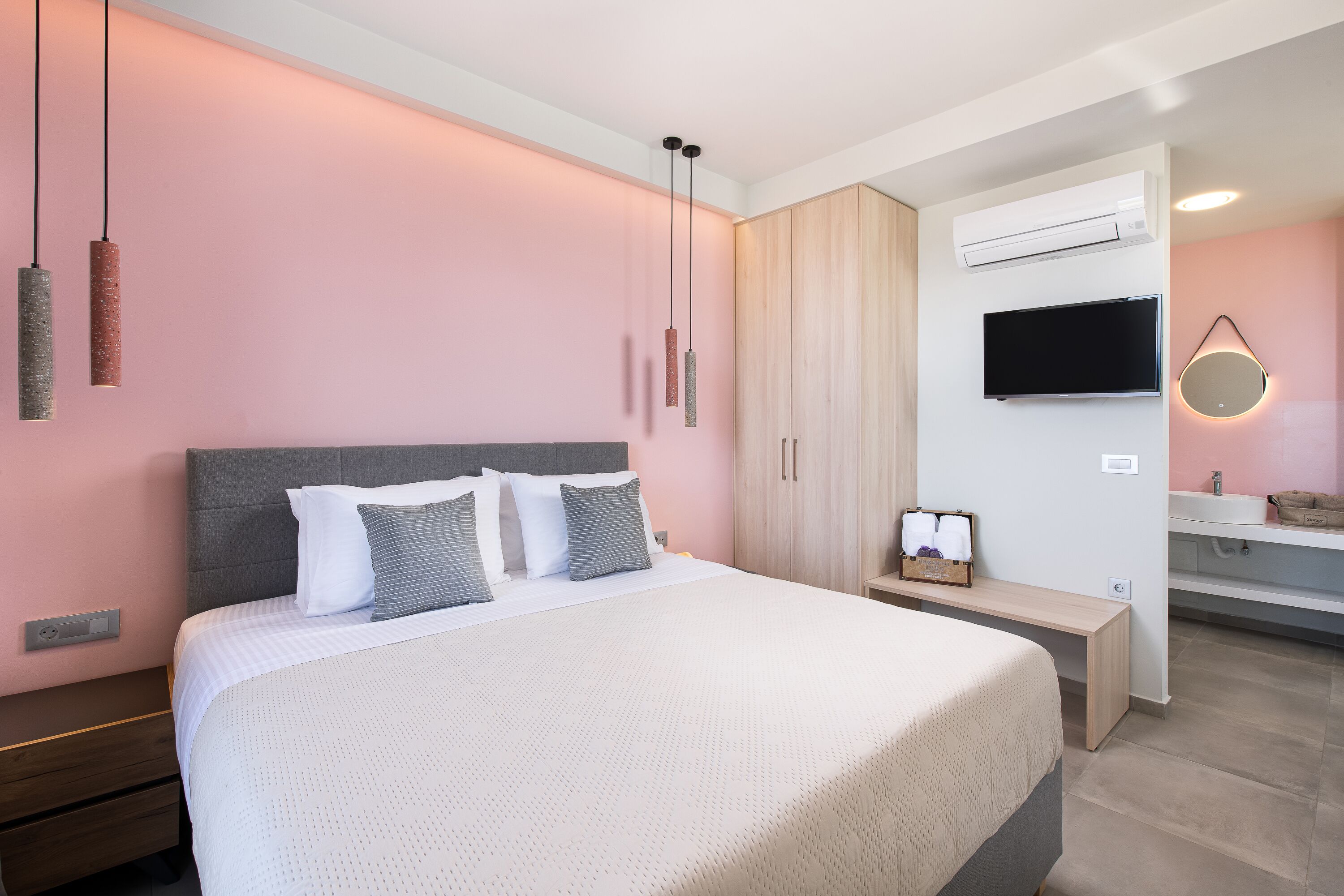 Un dormitorio moderno con una cama grande, mesitas de noche, un televisor y un banco empotrado.