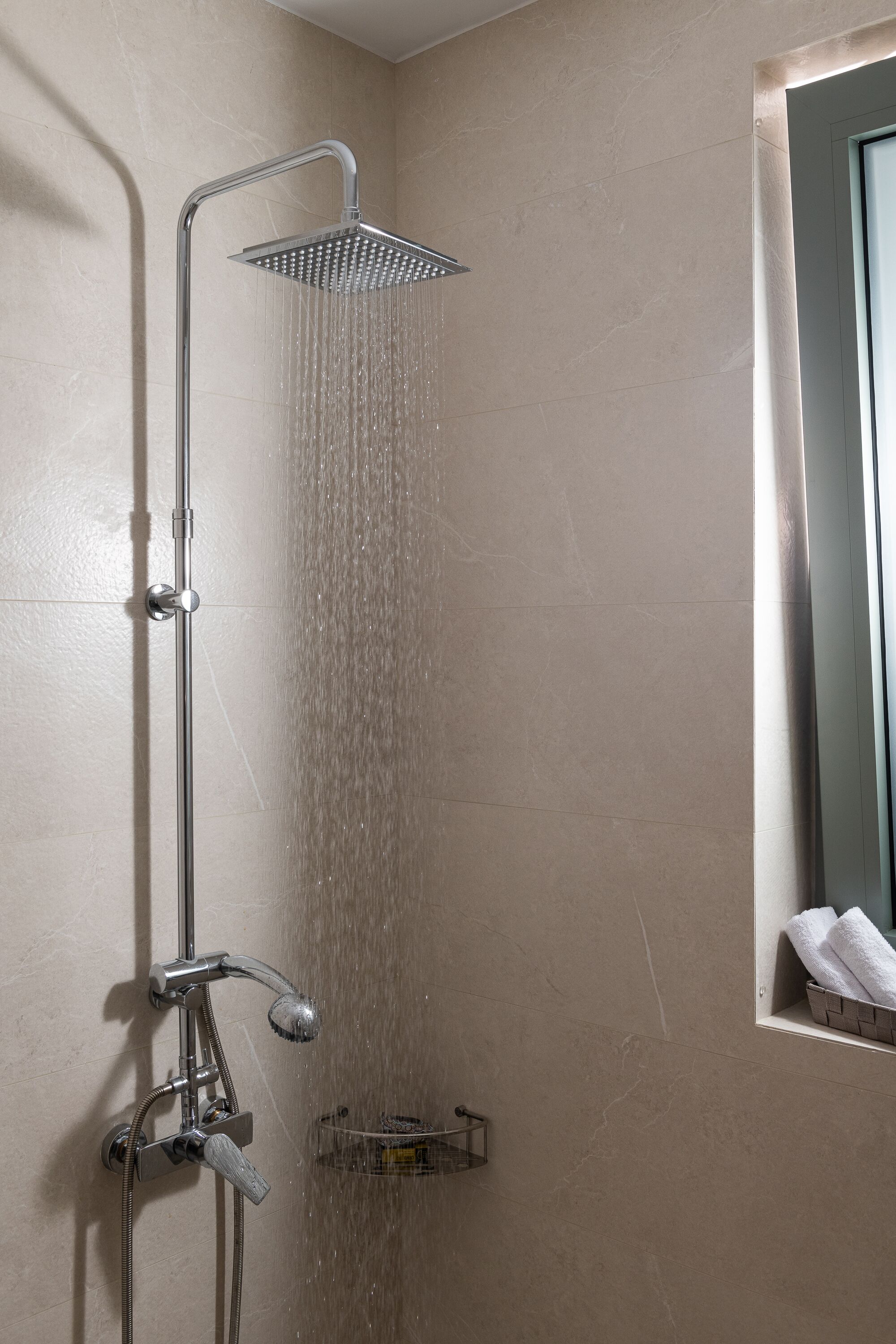 A shower with a handheld showerhead and a fixed showerhead, both mounted on a wall.