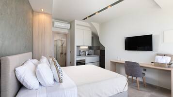 A modern hotel room with a large bed, a desk, and a TV.