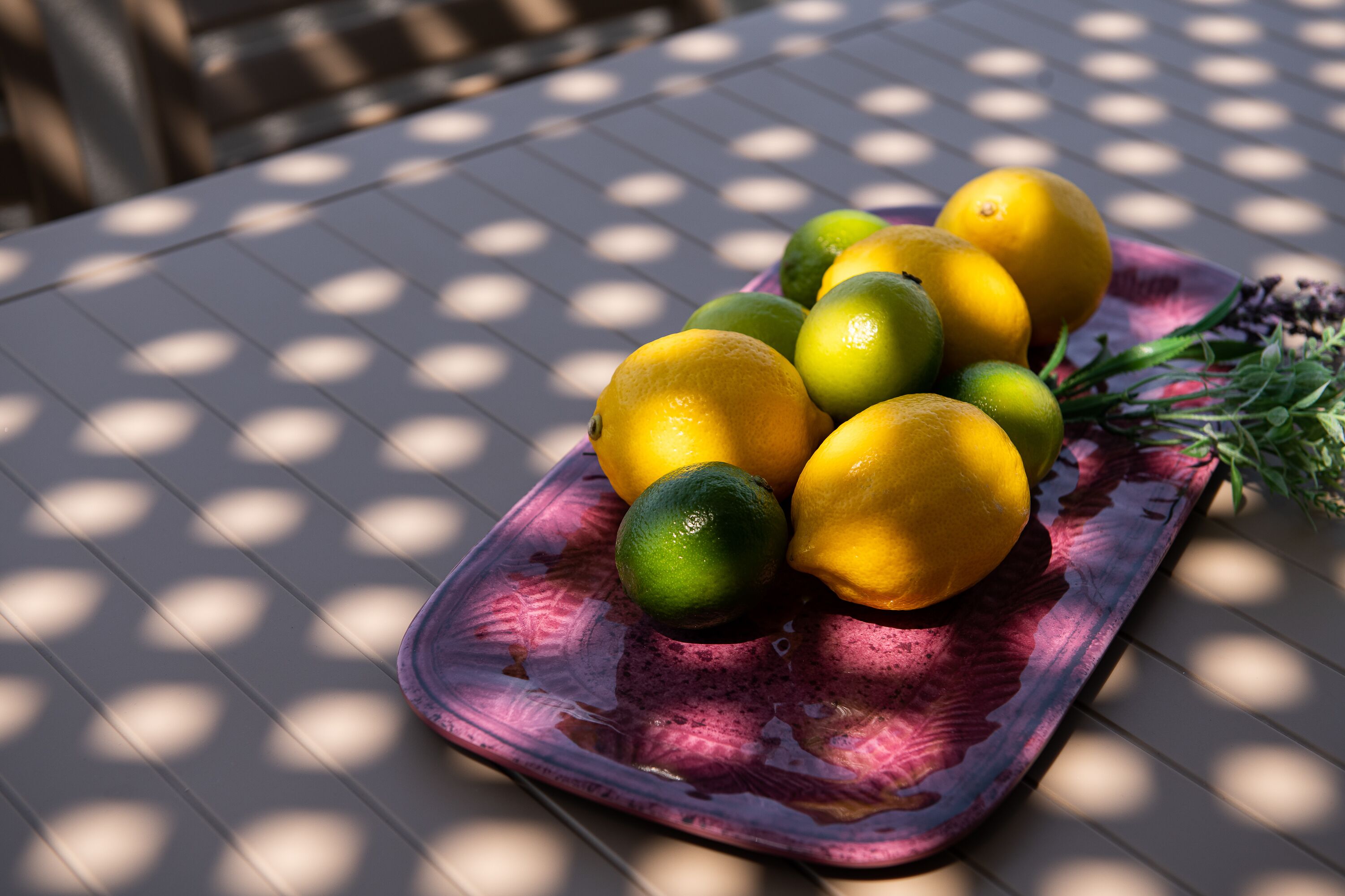 A table with a glass fruit tray containing lemons and limes.