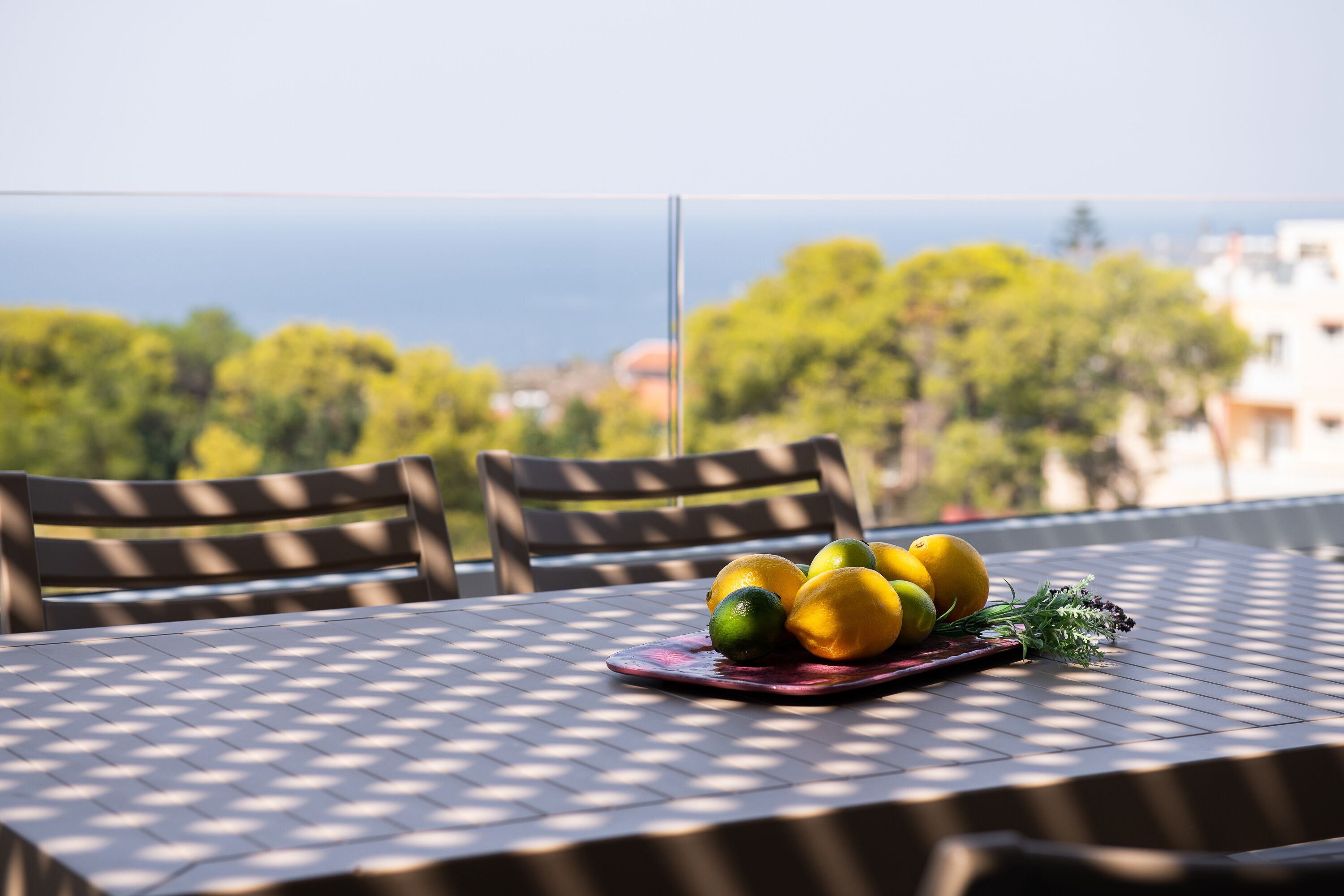 A table with a fruit arrangement and a view of the sea.