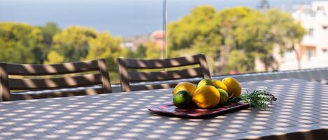 A table with a fruit arrangement and a view of the sea.