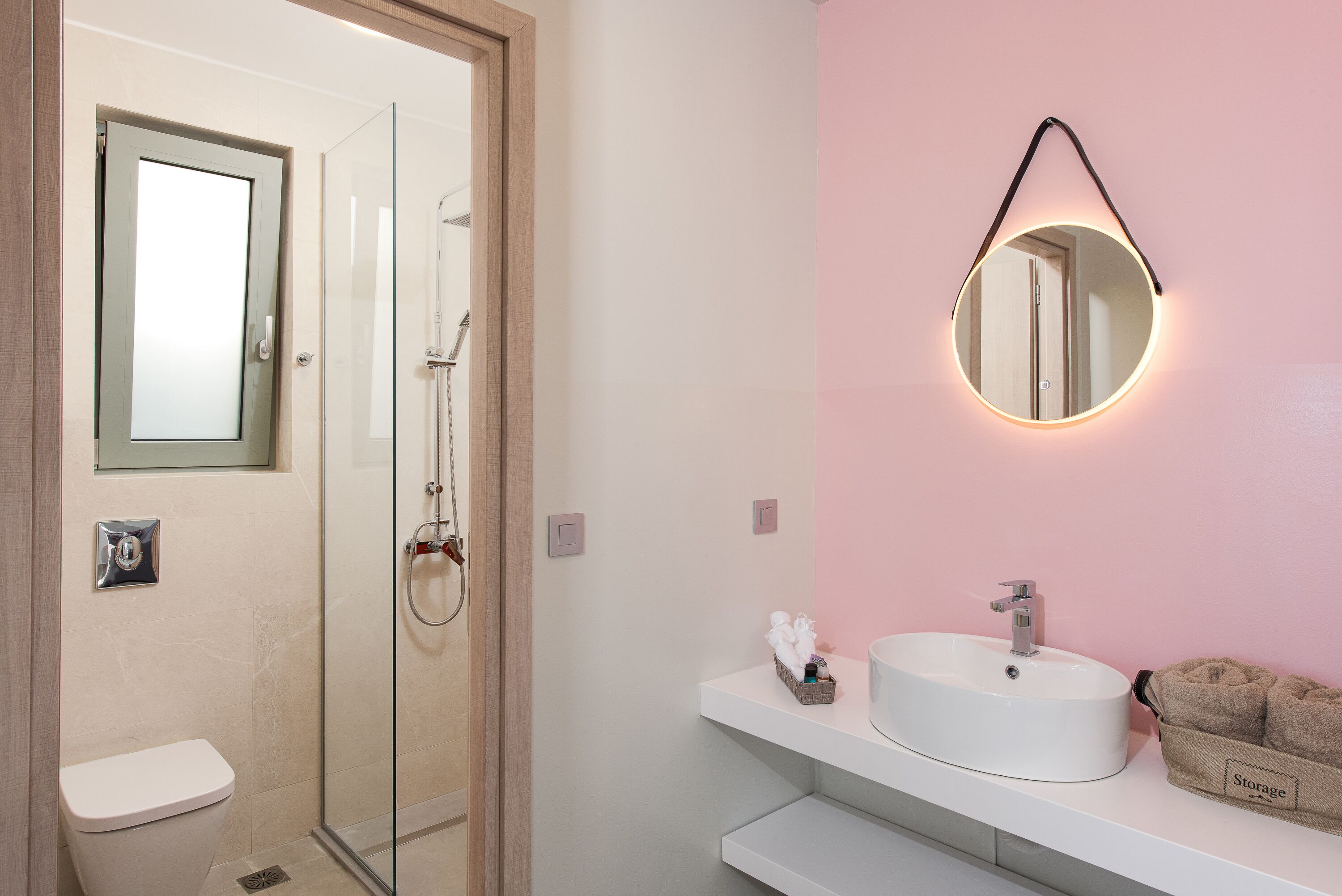 A bathroom with a glass shower enclosure, a white sink with a mirror, and a towel rack.