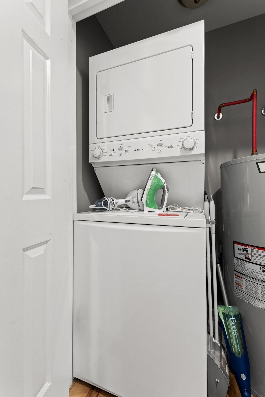 Une cuisine compacte avec un réfrigérateur blanc, un lave-linge blanc et un fer à repasser vert posé sur le plan de travail.