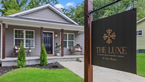 Ein Wohnhaus namens "The Luxe" von Armenteros Property Group, mit einer Veranda, die mit Blumentöpfen und Sitzgelegenheiten im Freien gestaltet ist.