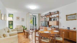 A living room with a sofa, a dining table set for four, and a kitchen area with cabinets and a refrigerator. - Refugio Madeirense by Atlantic Holiday (Funchal)