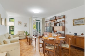A living room with a sofa, a dining table set for four, and a kitchen area with cabinets and a refrigerator. - Refugio Madeirense by Atlantic Holiday (Funchal)