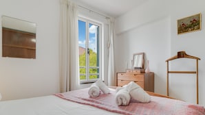 A hotel room with a bed, a dresser, a mirror, a window with curtains, and a painting on the wall. - Refugio Madeirense by Atlantic Holiday (Funchal)