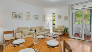 A dining area with a wooden table set for four, surrounded by two beige sofas. - Refugio Madeirense by Atlantic Holiday (Funchal)