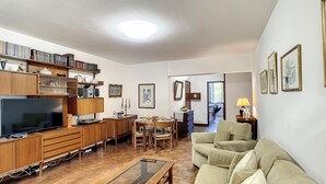 A spacious living room with a wooden coffee table, beige sofa, and a television. - Refugio Madeirense by Atlantic Holiday (Funchal)