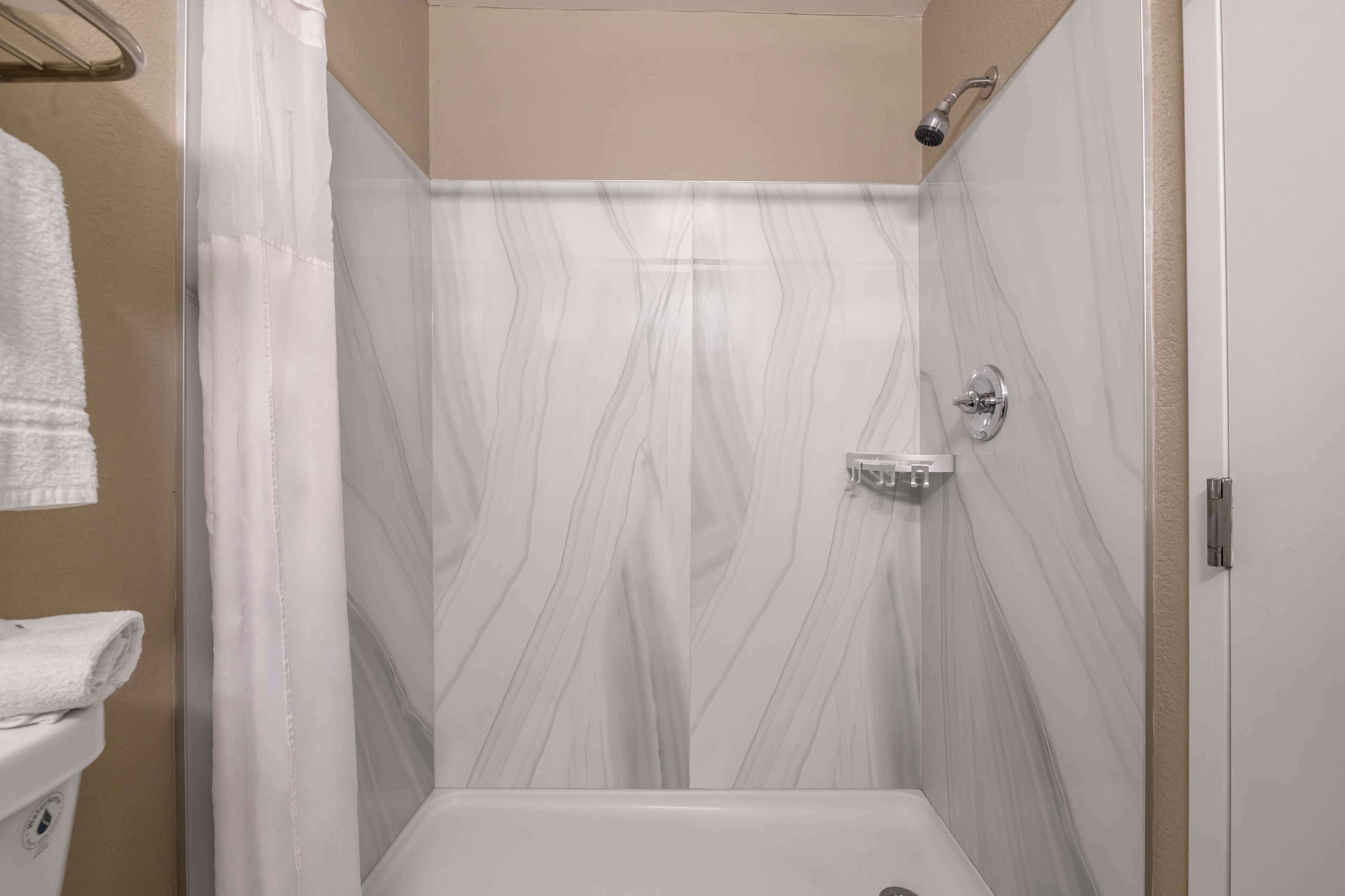 Un baño con ducha, inodoro y toallero.
