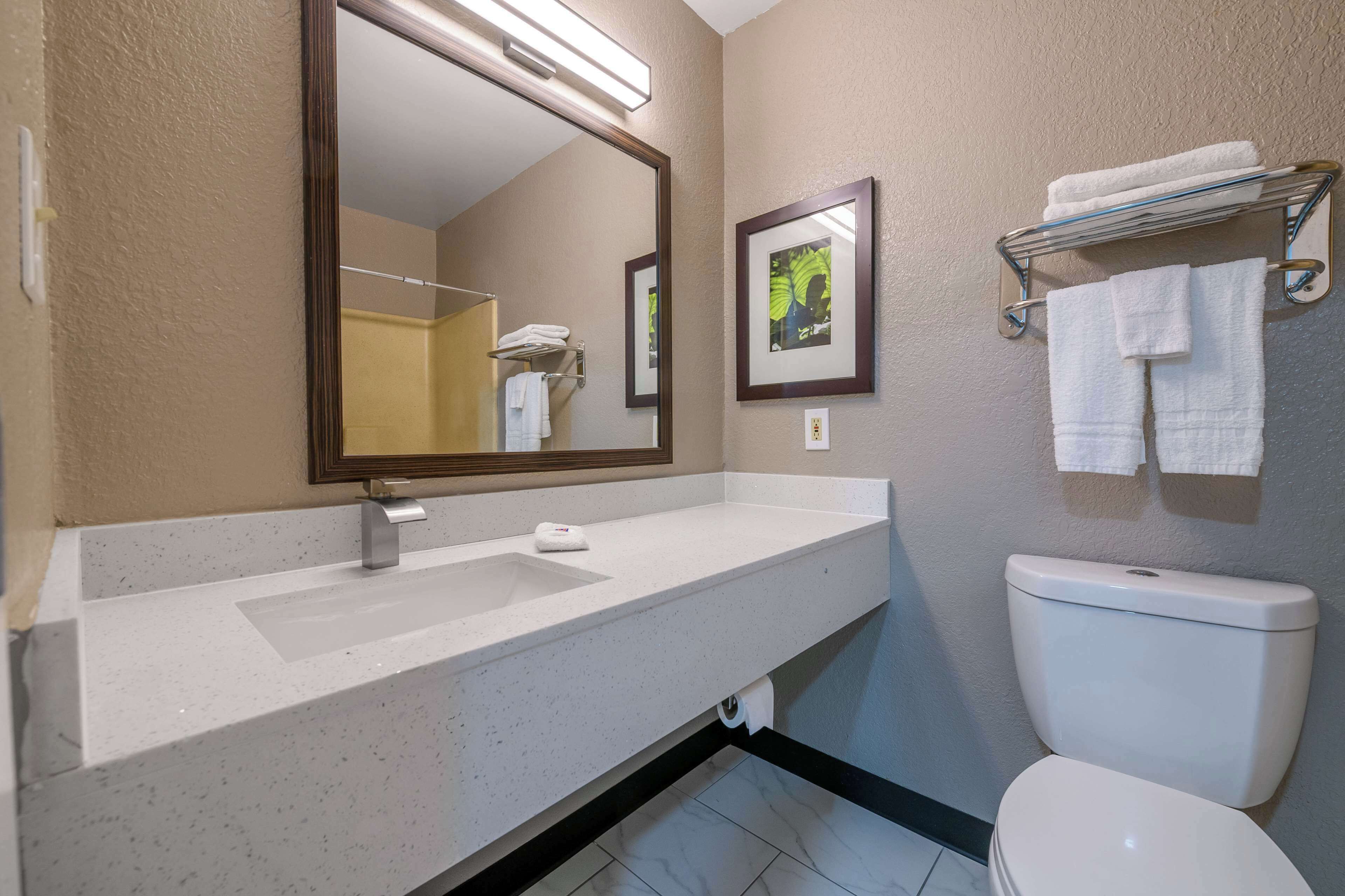 A bathroom with a white sink, a mirror, a toilet, and a towel rack.