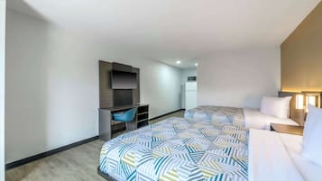 Une chambre d’hôtel avec un grand lit, un bureau avec une chaise, un téléviseur à écran plat et un four à micro-ondes.
