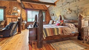 Interior acogedor de una cabaña de troncos con cama, sillón de masaje y chimenea rústica.