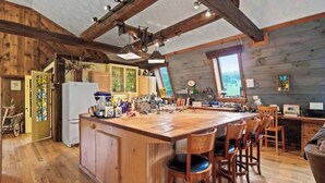 Una cocina amplia con una isla grande, armarios de madera y techo rústico.