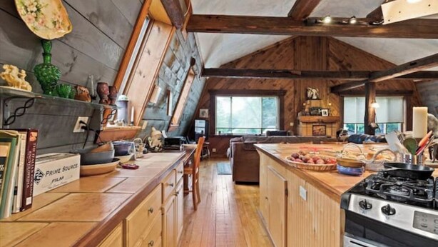Una cocina con armarios de madera, una estufa y un comedor con mesa y sillas.