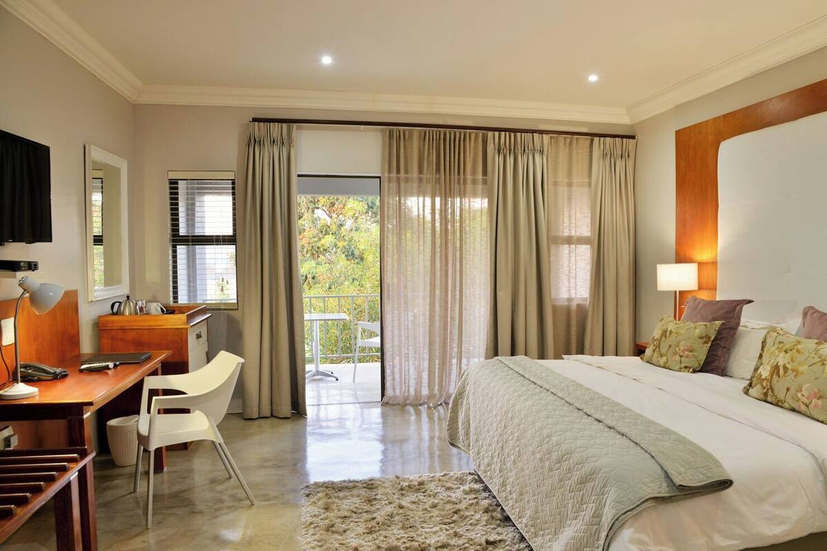 A hotel room with a bed, desk, chair, and a view of the outdoors.