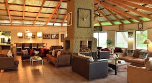 A spacious lounge area with multiple seating options, a fireplace, and a view of the outdoors.