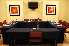 A conference room with a long table, chairs, water bottles, and framed pictures on the walls.