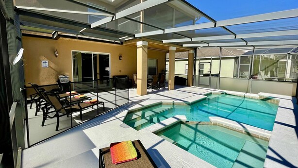 A rooftop pool area with a glass enclosure, lounge chairs, and a barbecue setup. - Suffolk Place (Davenport)