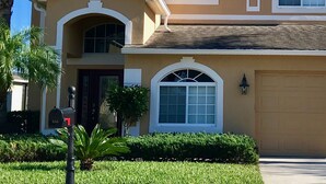 A two-story house with a beige exterior, white trim, and a garage. - Suffolk Place (Davenport)