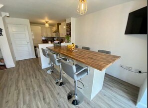 Enjoy casual dining and social gatherings in this modern kitchen and dining area, featuring a central island breakfast bar, oven, and flat-screen TV.