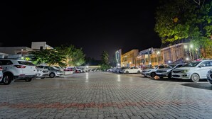 A parking lot with multiple cars and a building with illuminated windows in the background. - Itsy Hotels Sri Mani'S Residency, Coimbatore Airport (Coimbatore)