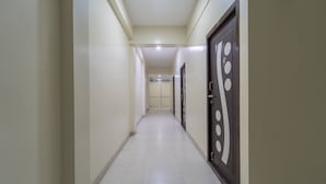 A long, narrow hallway with a tiled floor and plain walls. - Itsy Hotels Sri Mani'S Residency, Coimbatore Airport (Coimbatore)