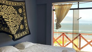 A bedroom with a bed, a tapestry, and a view of the beach. - Hospedaje Sueños DE Chicama, MAS Cerca AL Point, CON UNA Vista Expectacular (LA LIBERTAD)