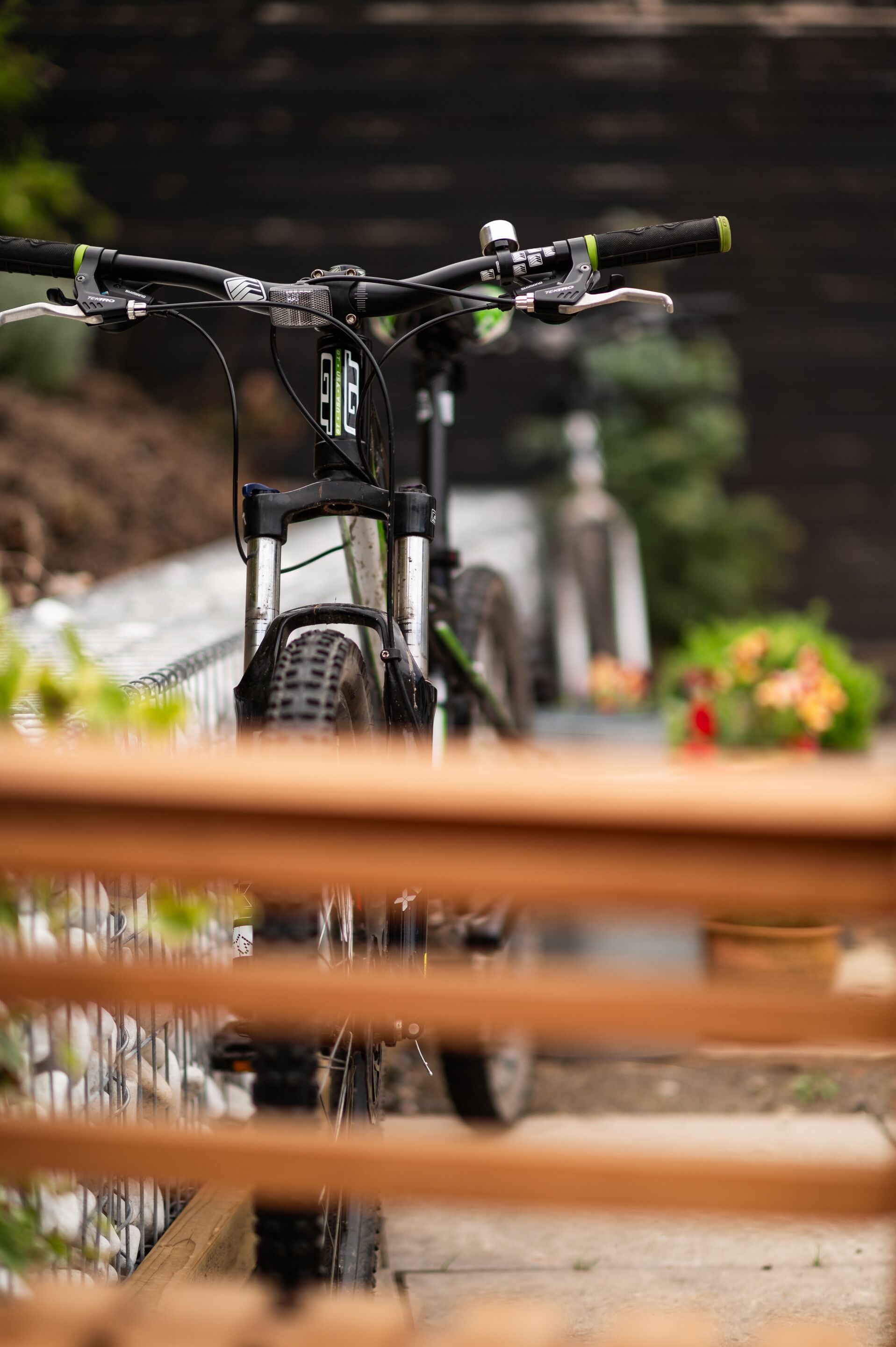 A bicycle parked in a covered area with a wooden railing in the foreground.