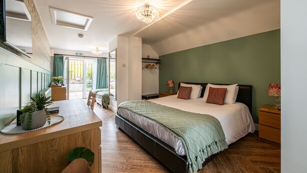 A bedroom with a bed, bedside table, and a view of the outside. - Stonehenge Courtyard (Salisbury)