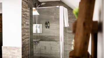 A glass-enclosed shower with a modern design, a built-in sink, and a towel rack.