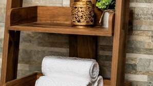 A wooden shelf with a potted plant, a decorative container, and rolled towels. - Stonehenge Courtyard (Salisbury)