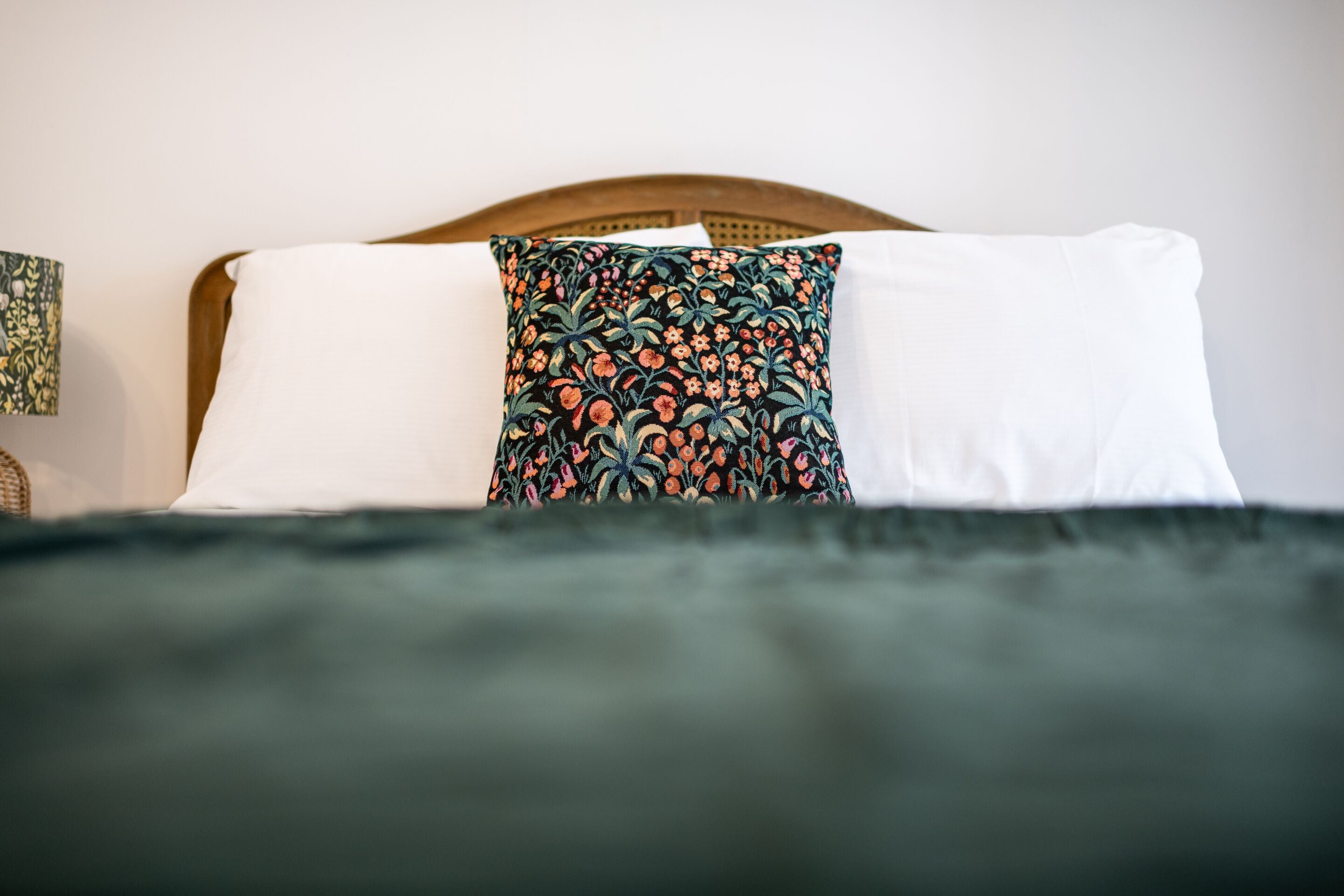 A bed with two pillows, one plain white and one with a floral pattern.