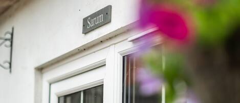 Un edificio blanco con un letrero que dice “Sarum” sobre una ventana.