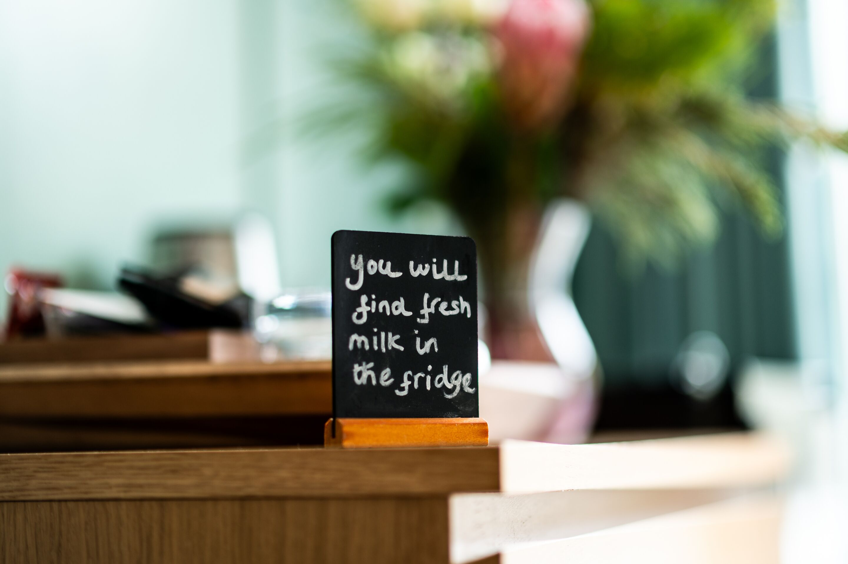 A sign on a counter with the message "you will find fresh milk in the fridge."
