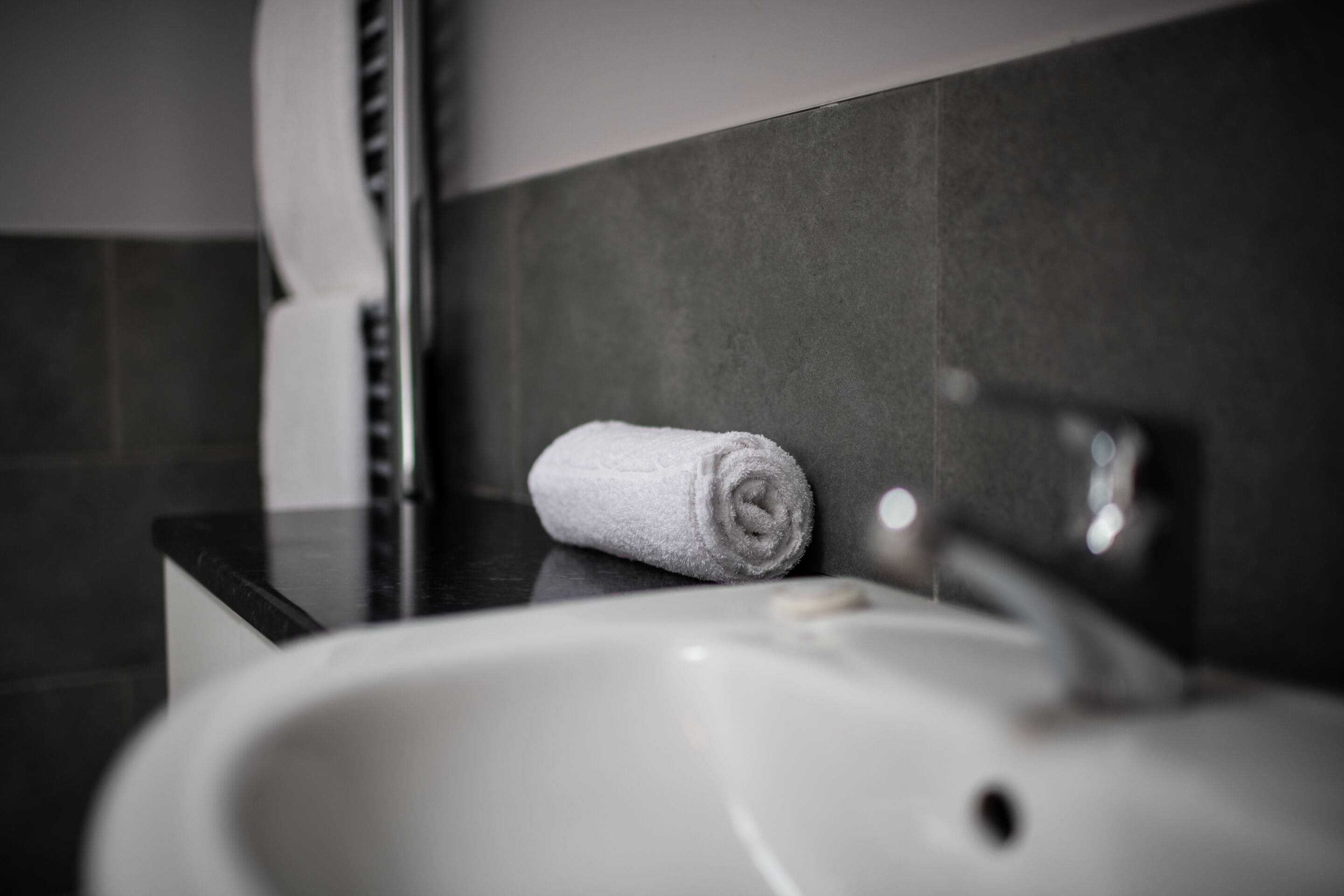Ein Badezimmer mit einem weißen Waschbecken, einem Handtuch und einer Seifenspender.