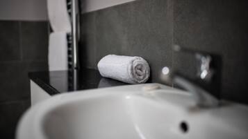 Ein Badezimmer mit einem weißen Waschbecken, einem Handtuch und einer Seifenspender.