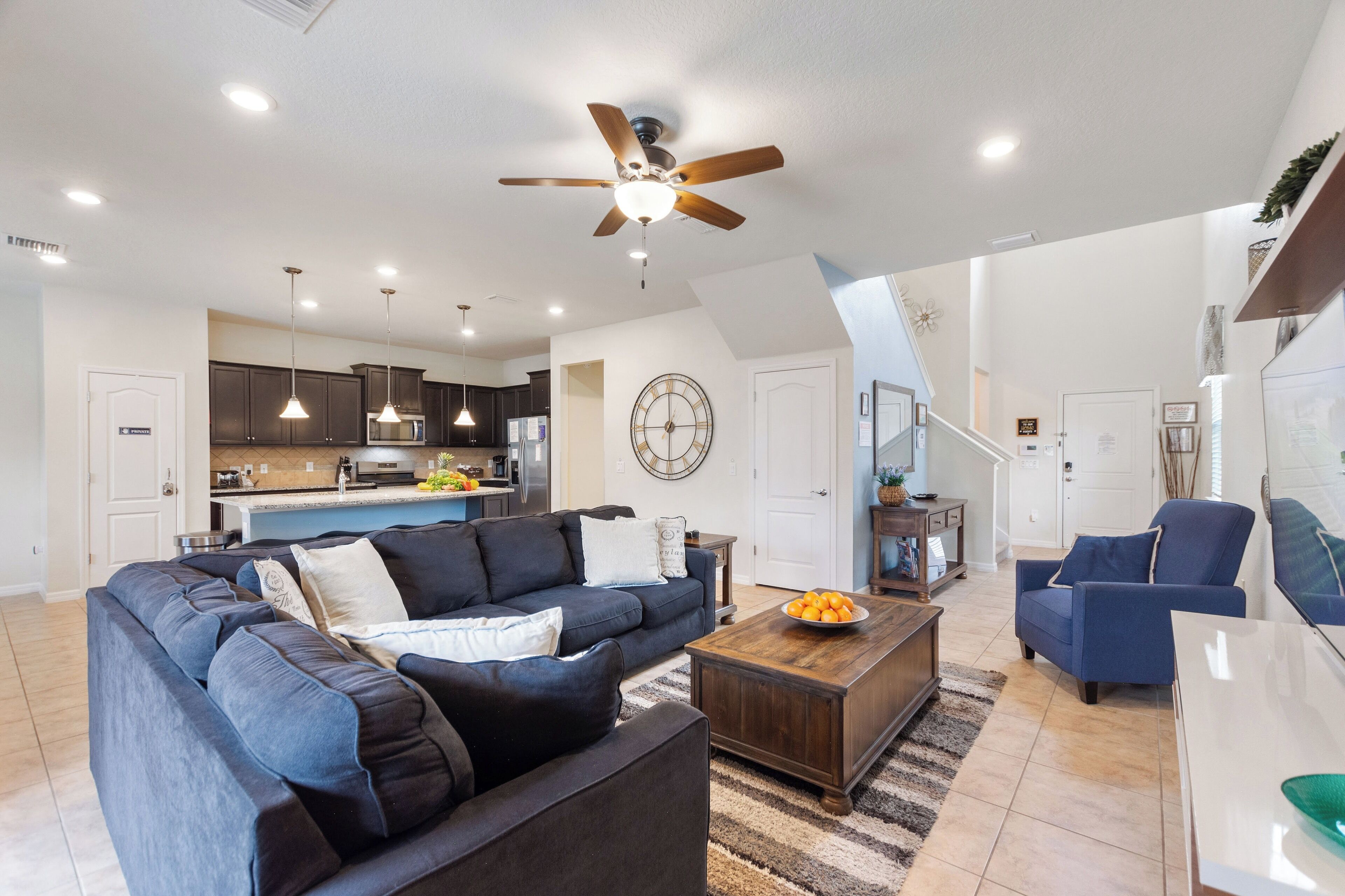 A modern living room with a sectional sofa, a coffee table, and a ceiling fan.