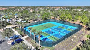 An aerial view of a tennis court surrounded by trees and residential buildings. - Anchor Cove Villa (Davenport)