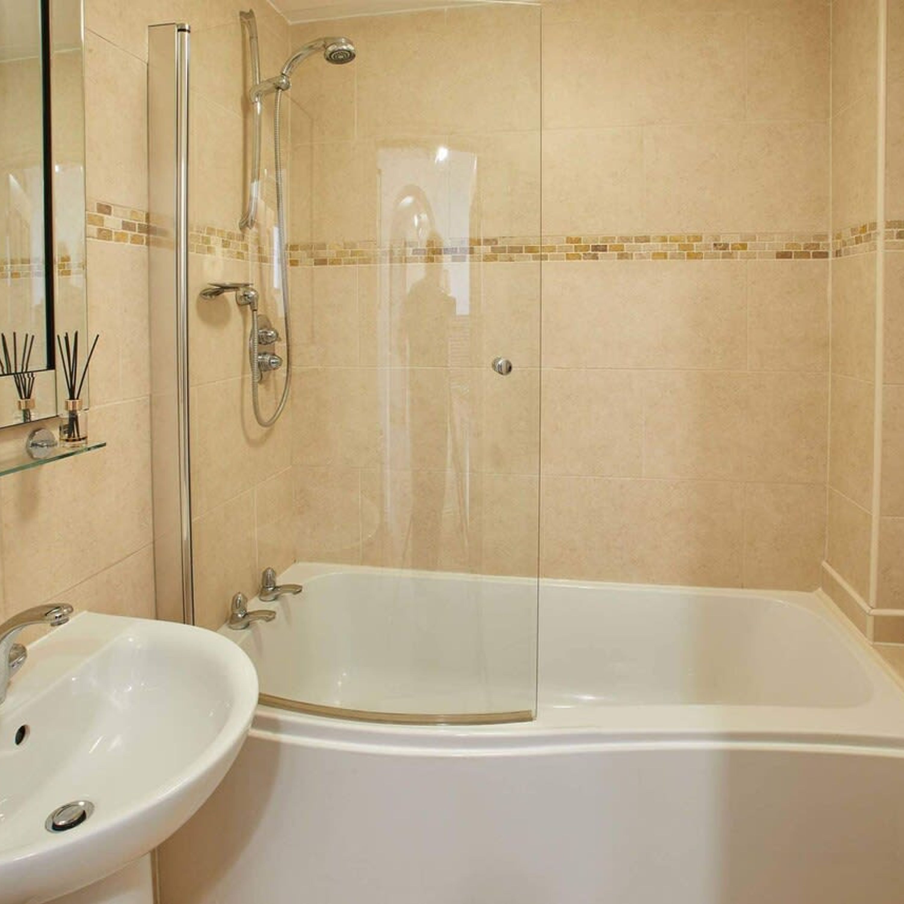 A bathroom with a glass-enclosed shower, a white bathtub, and a sink with a mirror above it.