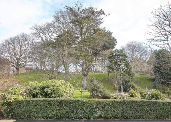A landscaped garden with various trees and shrubs, a well-maintained hedge, and a grassy area. - Host Stay Park View Apartment (Whitby)