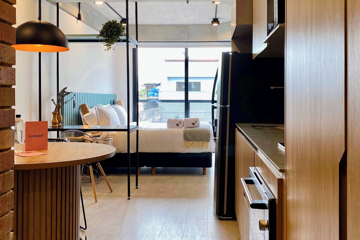 Une chambre d’hôtel moderne équipée d’un lit, d’un bureau, d’une télévision et offrant une vue sur l’extérieur.