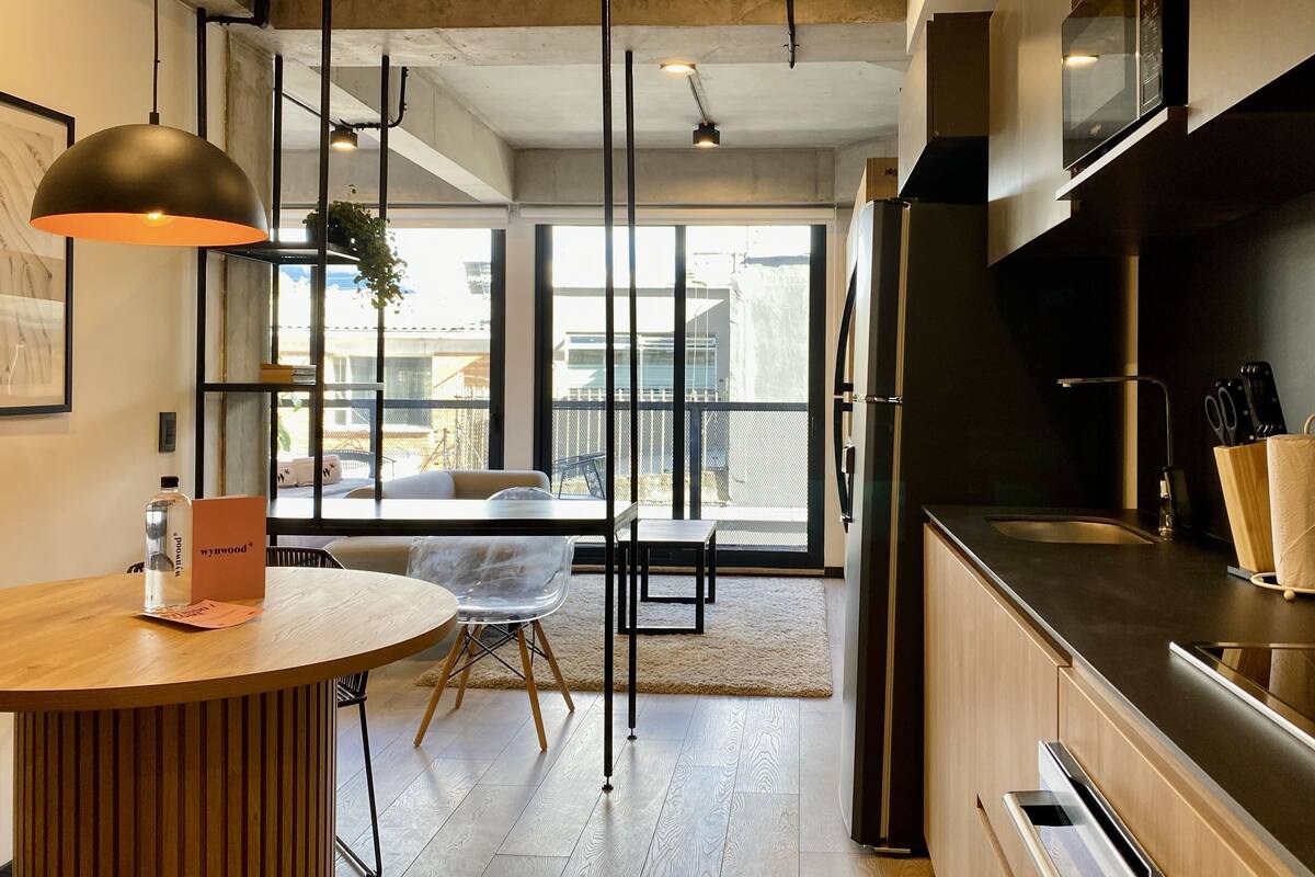 Une cuisine moderne dotée d’un plan de travail en bois, d’un four encastré et d’une grande fenêtre donnant sur un balcon.