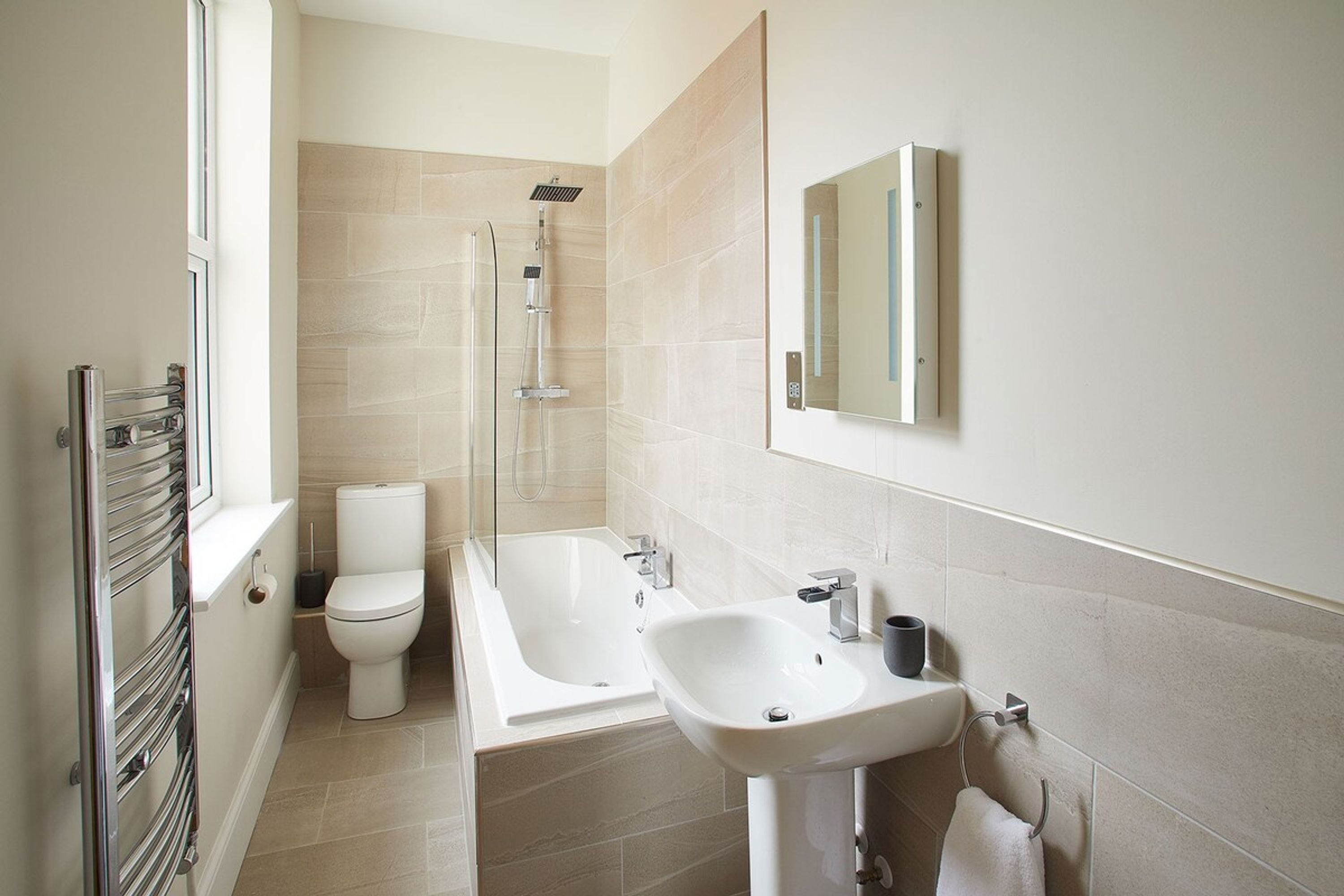 A modern bathroom with a toilet, bathtub, and sink.