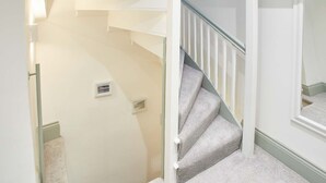 A staircase with white walls and a carpeted landing. - Host Stay Threadneedle Cottage (Whitby)